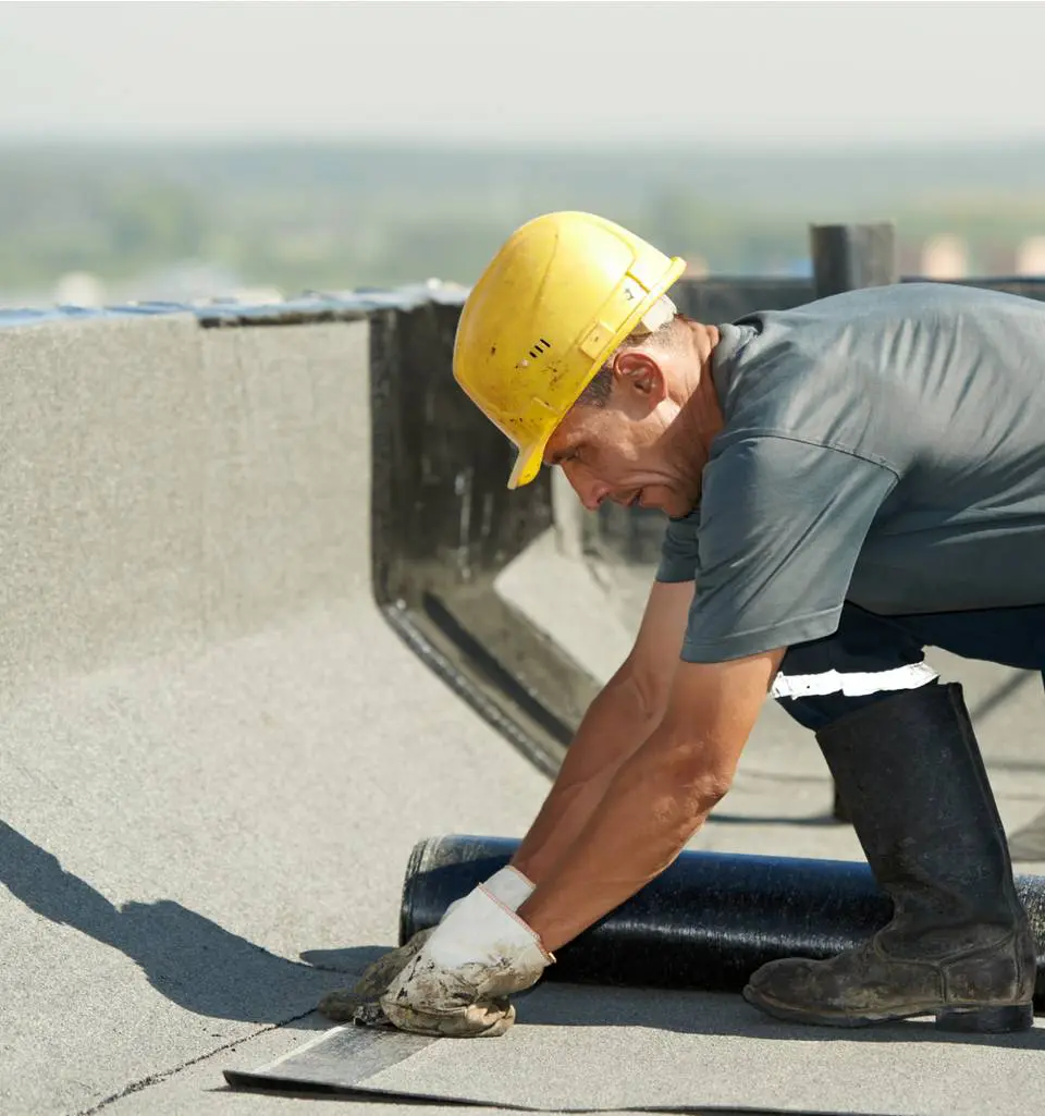 Worker installing roofing material on a roof.