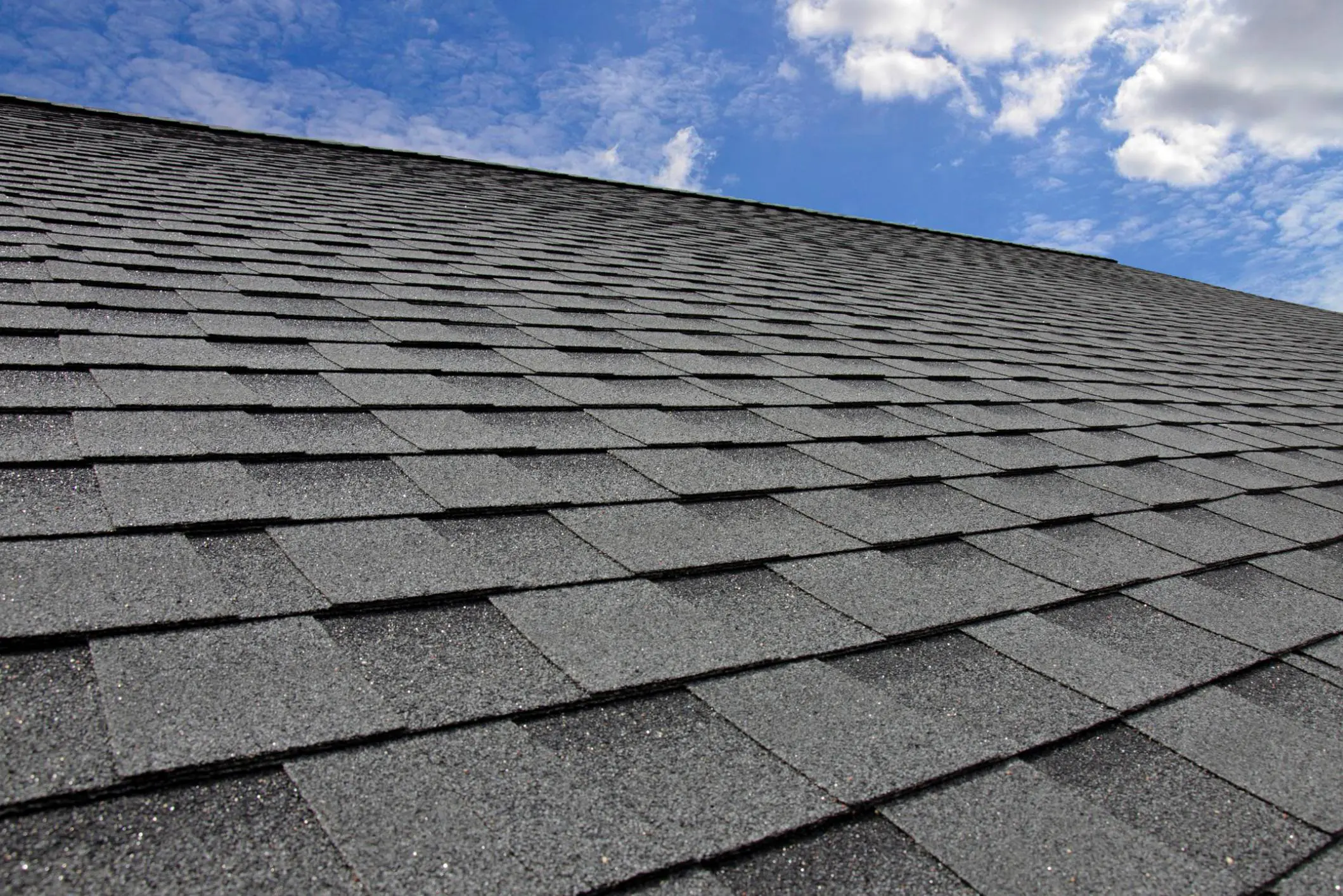 Gray shingle roof under a blue sky.